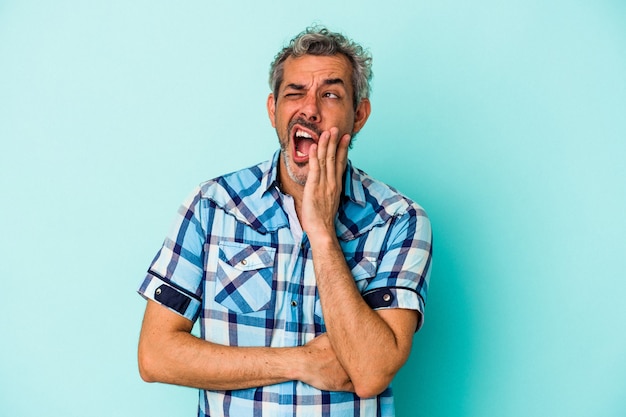 Middle age caucasian man isolated on blue background  yawning showing a tired gesture covering mouth with hand.