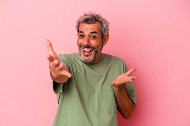 Middle age caucasian man isolated on pink background  feels confident giving a hug to the camera.