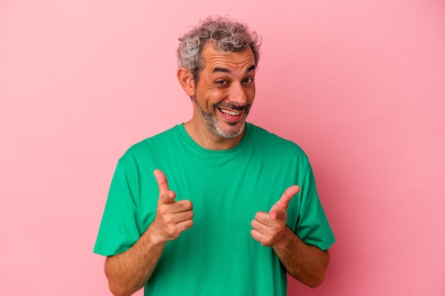 Middle age caucasian man isolated on pink background  pointing to front with fingers.