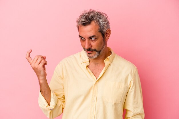 Middle age caucasian man isolated on pink background  pointing with finger at you as if inviting come closer.