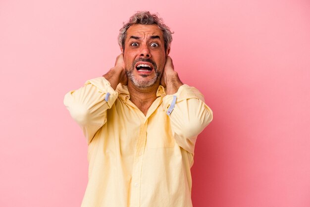 Middle age caucasian man isolated on pink background screaming with rage