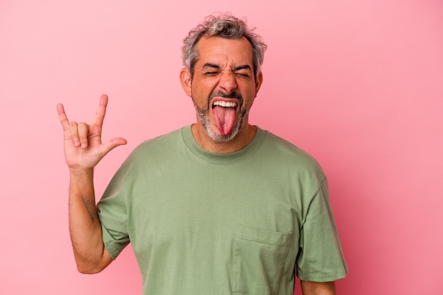 Middle age caucasian man isolated on pink background  showing rock gesture with fingers