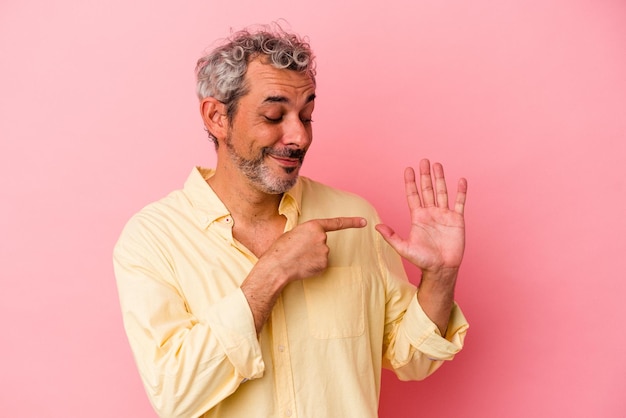 Белый мужчина средних лет изолирован на розовом фоне, весело улыбаясь, показывая пальцами номер пять