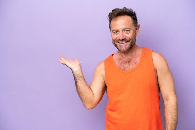 Middle age caucasian man isolated on purple background holding copyspace imaginary on the palm to insert an ad