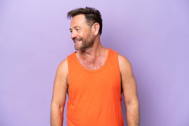 Middle age caucasian man isolated on purple background looking side