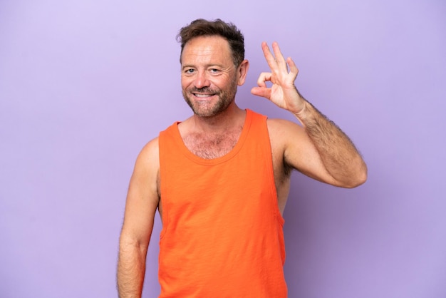 Middle age caucasian man isolated on purple background showing ok sign with fingers
