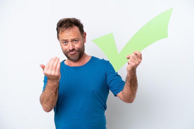 Middle age caucasian man isolated on white background holding a check icon and doing coming gesture