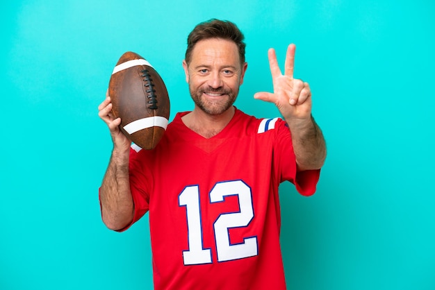 Middle age caucasian man playing rugby isolated on blue background happy and counting three with fingers