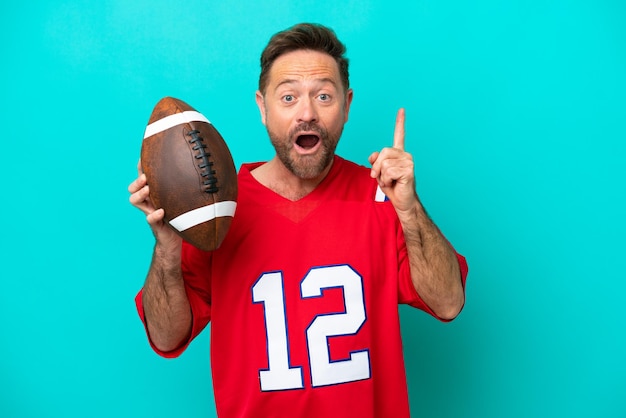 Middle age caucasian man playing rugby isolated on blue background intending to realizes the solution while lifting a finger up