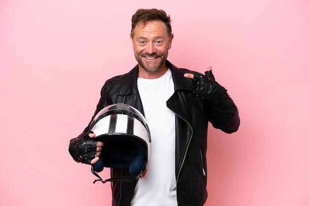 Middle age caucasian man with a motorcycle helmet isolated on pink background giving a thumbs up gesture