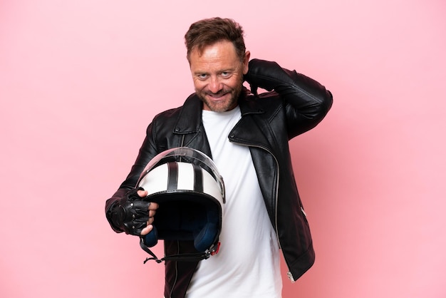 Middle age caucasian man with a motorcycle helmet isolated on pink background laughing