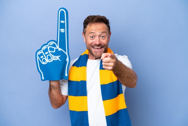 Middle age caucasian sports fan man isolated on blue background surprised and pointing front