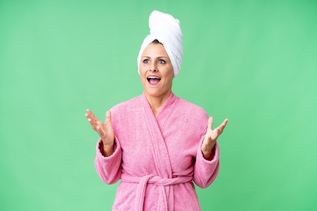 Middle age caucasian woman in a bathrobe over isolated background with surprise facial expression