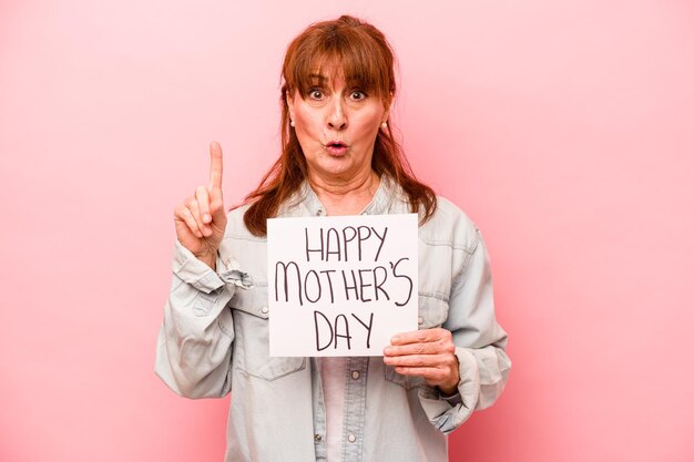 Middle age caucasian woman holding Happy mother's day placard isolated on pink background having some great idea concept of creativity