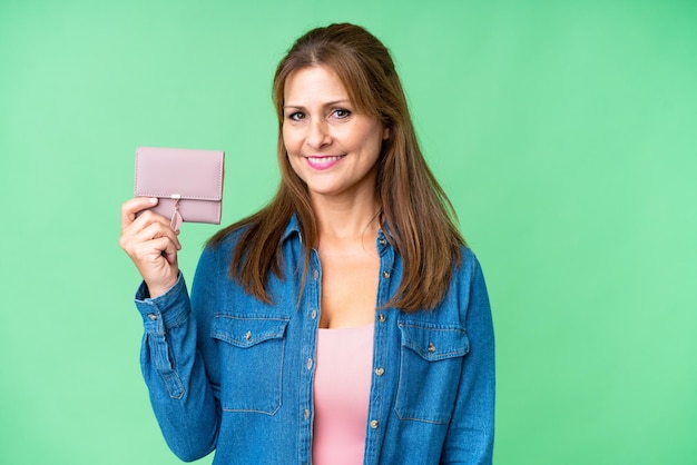 Middle age caucasian woman holding wallet over isolated background smiling a lot