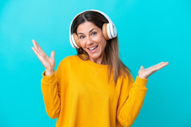 Middle age caucasian woman isolated on blue background surprised and listening music