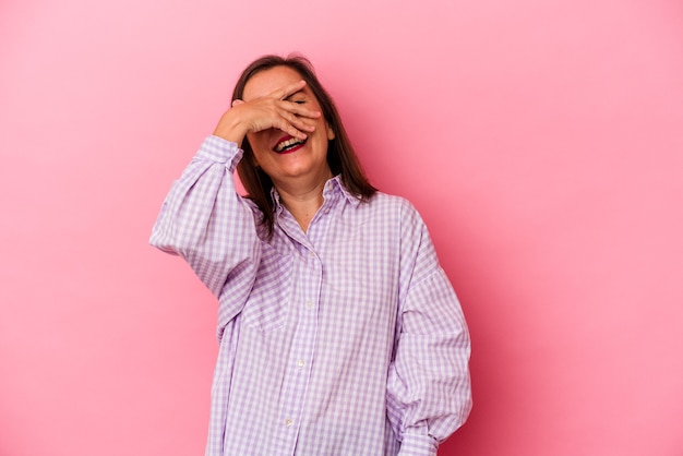 Middle age caucasian woman isolated on pink background covers eyes with hands, smiles broadly waiting for a surprise.