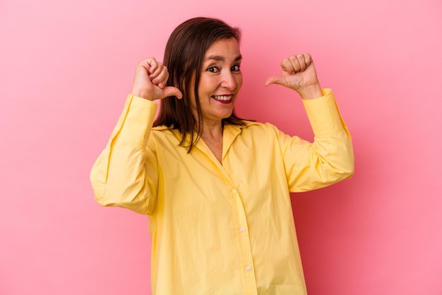 Middle age caucasian woman isolated on pink background feels proud and self confident, example to follow.