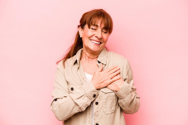 Middle age caucasian woman isolated on pink background has friendly expression pressing palm to chest Love concept