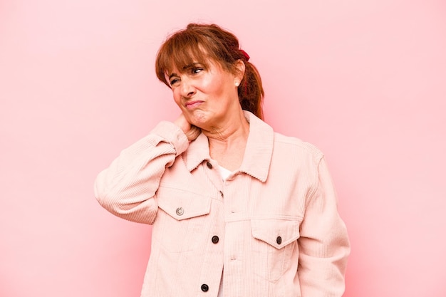Middle age caucasian woman isolated on pink background having a neck pain due to stress massaging and touching it with hand