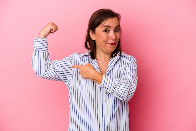 Foto donna caucasica di mezza età isolata su sfondo rosa che mostra un gesto di forza con le braccia, simbolo del potere femminile