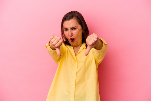 Middle age caucasian woman isolated on pink background showing thumb down and expressing dislike