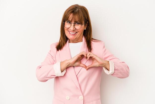 Middle age caucasian woman isolated on white background smiling and showing a heart shape with hands.