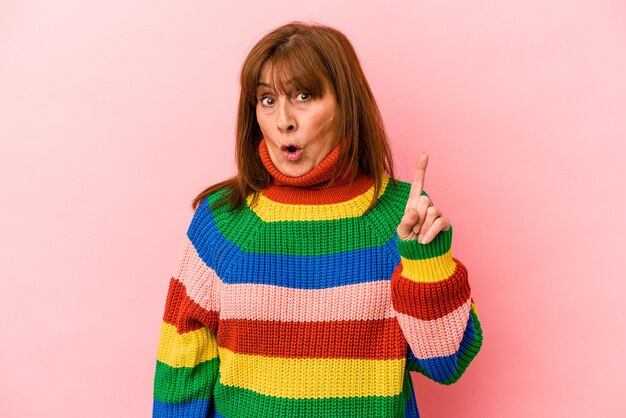 Middle age caucasian woman wearing a multicolor sweater isolated on pink background having some great idea, concept of creativity.