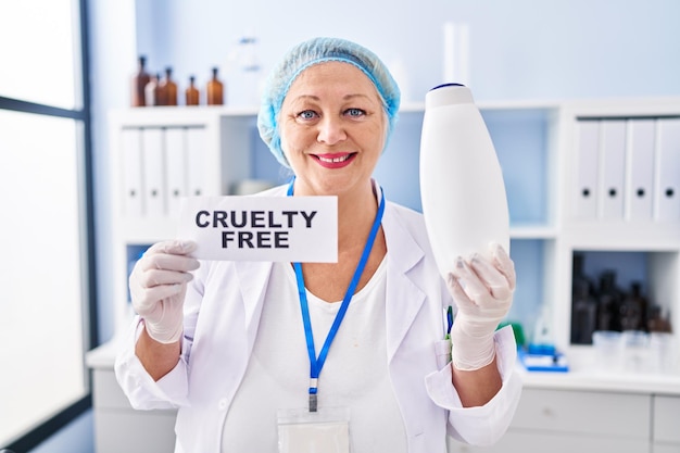 Белая женщина средних лет, работающая в лаборатории без жестокости, улыбается с счастливой и прохладной улыбкой на лице, показывая зубы.