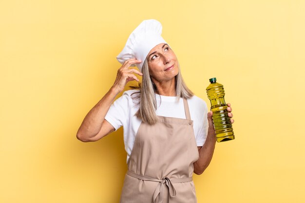 Middle age chef woman feeling puzzled and confused, scratching head and looking to the side