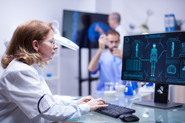 Middle age chief of staff typing the report on human research. Scientist working in laborator.