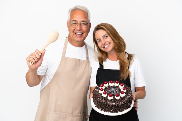 Middle age couple chef holding birthday cake isolated on white background