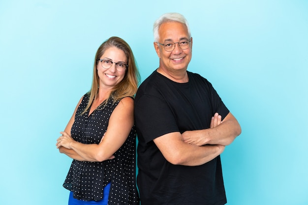 Middle age couple isolated on blue background keeping arms crossed