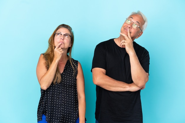 Middle age couple isolated on blue background standing and thinking an idea