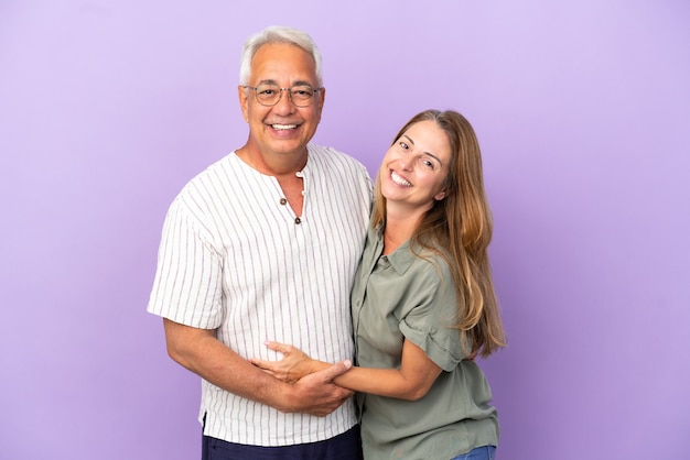 Middle age couple isolated on purple background hugging