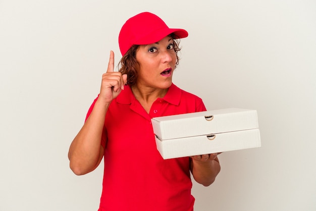 Middle age delivery woman taking pizzas isolated on white background having an idea, inspiration concept.