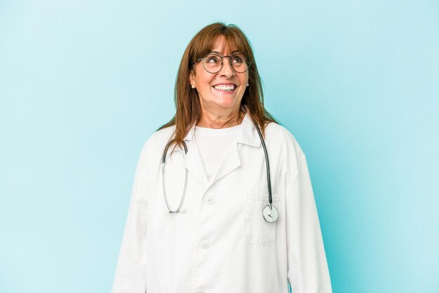 Middle age doctor woman isolated on pink background dreaming of achieving goals and purposes