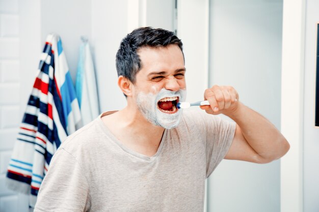 Foto padre di mezza età spazzolatura dei denti la mattina in bagno