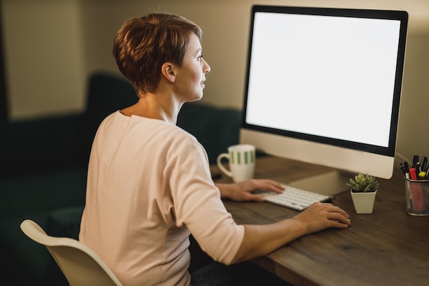 Photo middle age female freelancer working late on computer in her home office during pandemic quarantine.