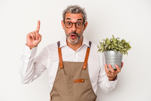 Middle age gardener caucasian man holding a plant isolated on white background having an idea inspiration concept