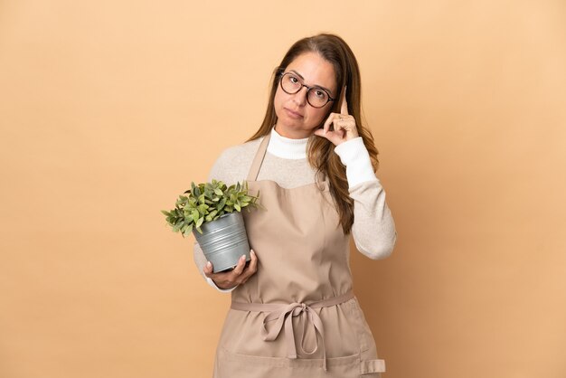 孤立した植物を保持している中年の庭師の女性