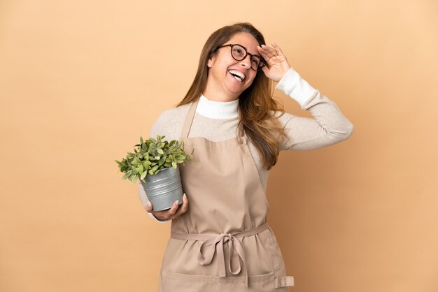 Photo middle age gardener woman holding a plant isolated