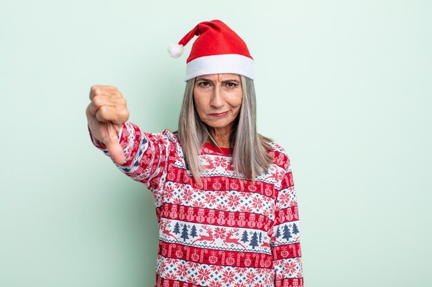 Женщина среднего возраста седые волосы чувство креста, показывая большие пальцы руки вниз. рождественская концепция