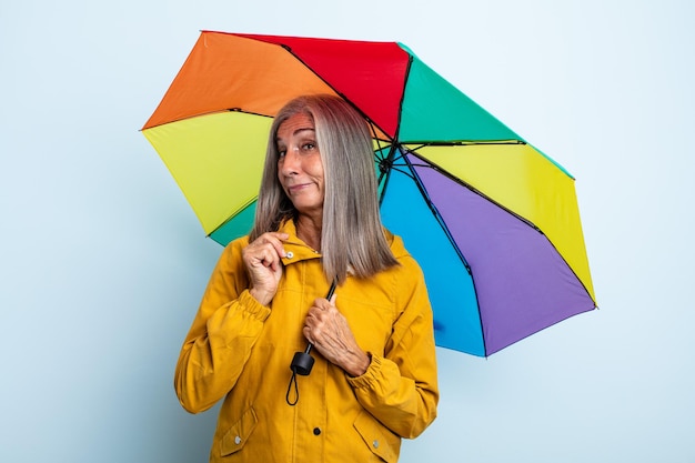 Middle age gray hair woman looking arrogant, successful, positive and proud. umbrella and rain concept