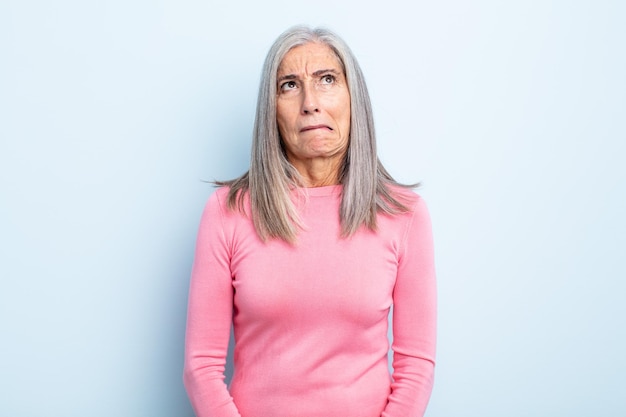 Middle age gray hair woman looking goofy and funny with a silly cross-eyed expression, joking and fooling around