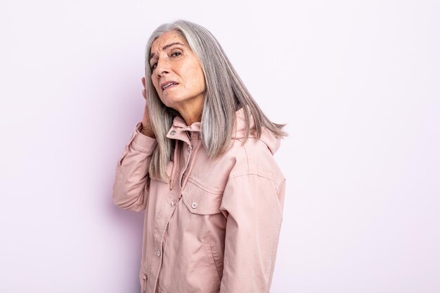 Donna di mezza età con i capelli grigi che sembra seria e curiosa, ascolta, cerca di ascoltare una conversazione segreta o un pettegolezzo, origliare
