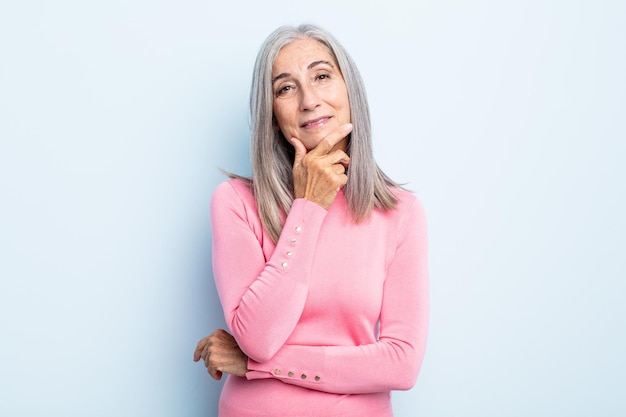 Middle age gray hair woman looking serious, thoughtful and distrustful, with one arm crossed and hand on chin, weighting options