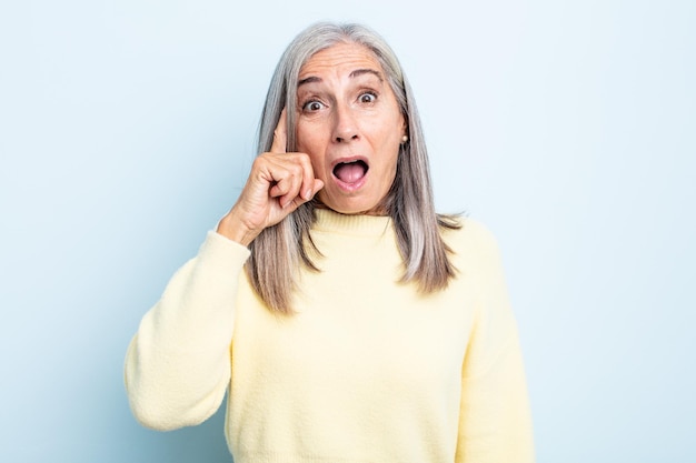 Middle age gray hair woman looking surprised, open-mouthed, shocked, realizing a new thought, idea or concept