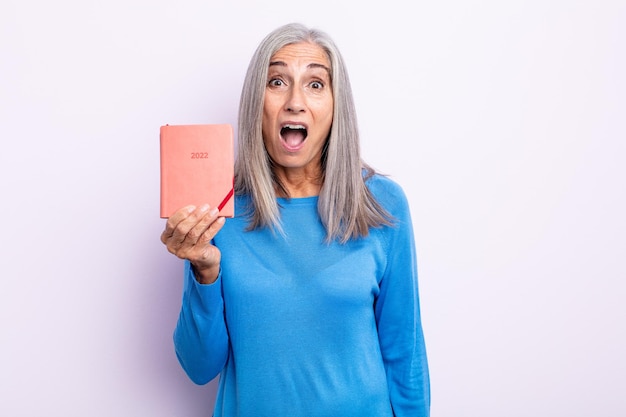 Middle age gray hair woman looking very shocked or surprised. 2022 agenda concept