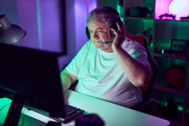 Photo middle age greyhaired man streamer playing video game using computer at gaming room